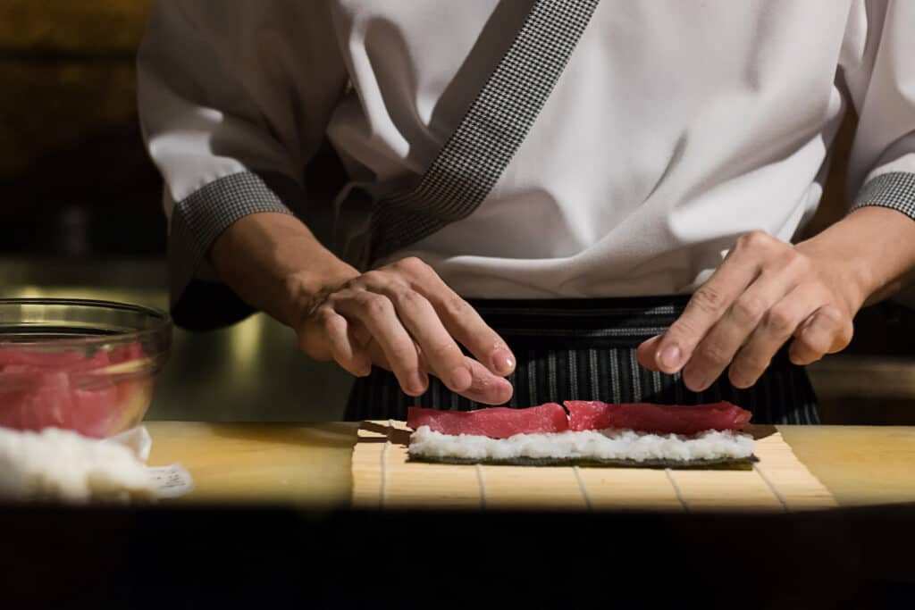 Chef Japanese cuisine in hotel or restaurant kitchen cooking, only hands. He is working sushi