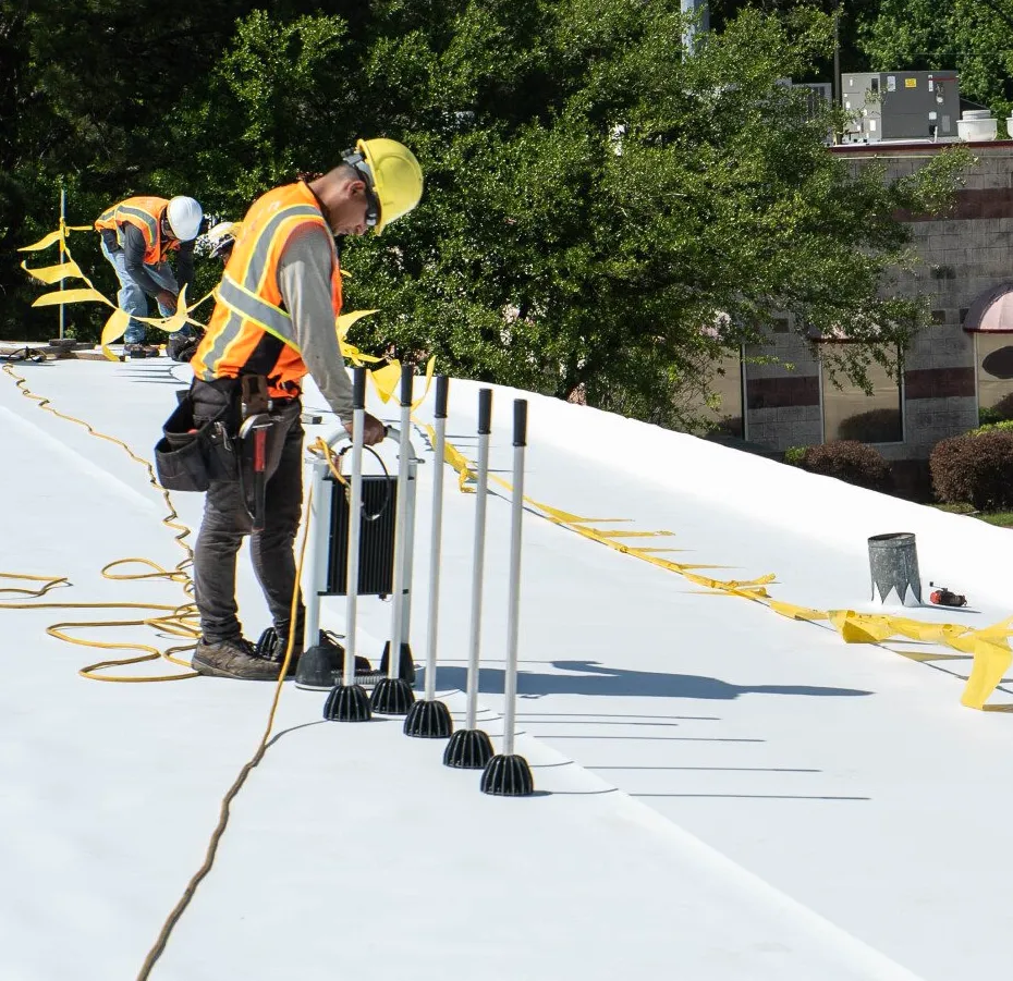 contractors in hard hats use tools to install flat roof