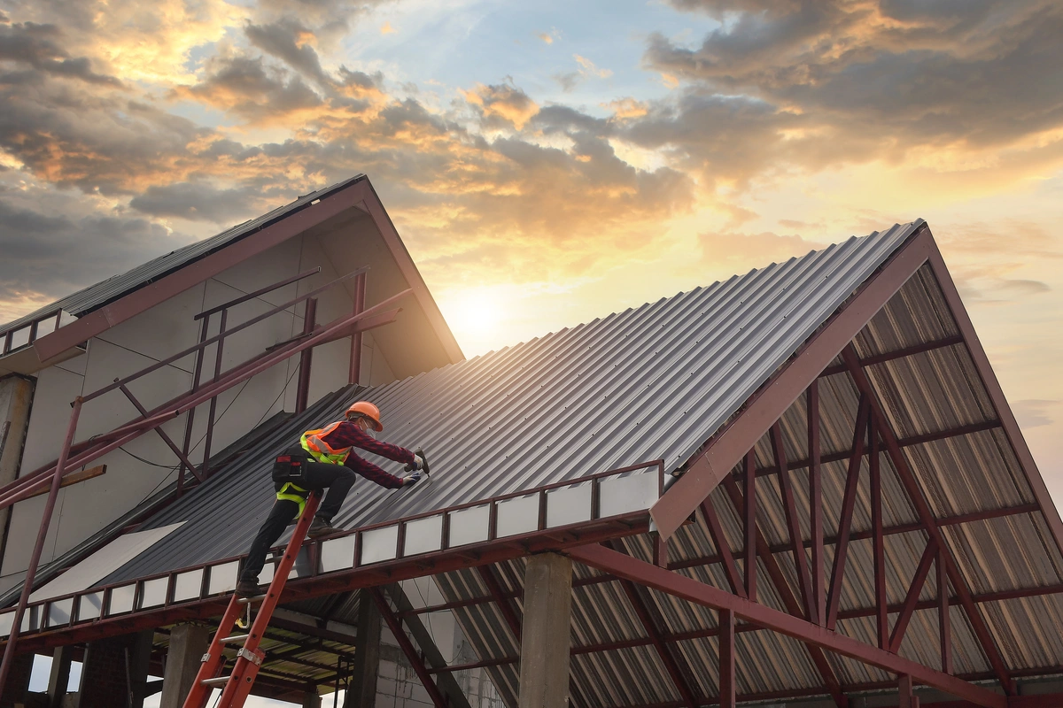 custom metal roofing-roof tech standing on ladder installing metal roofing