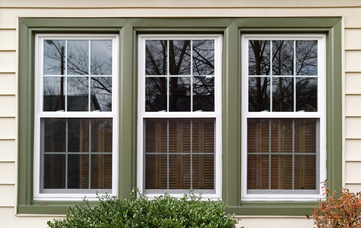 window replacement-close up of white siding with green trim around new windows