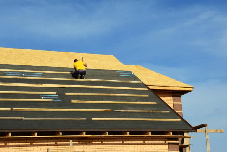 a roof tech applying underlayment to a roof