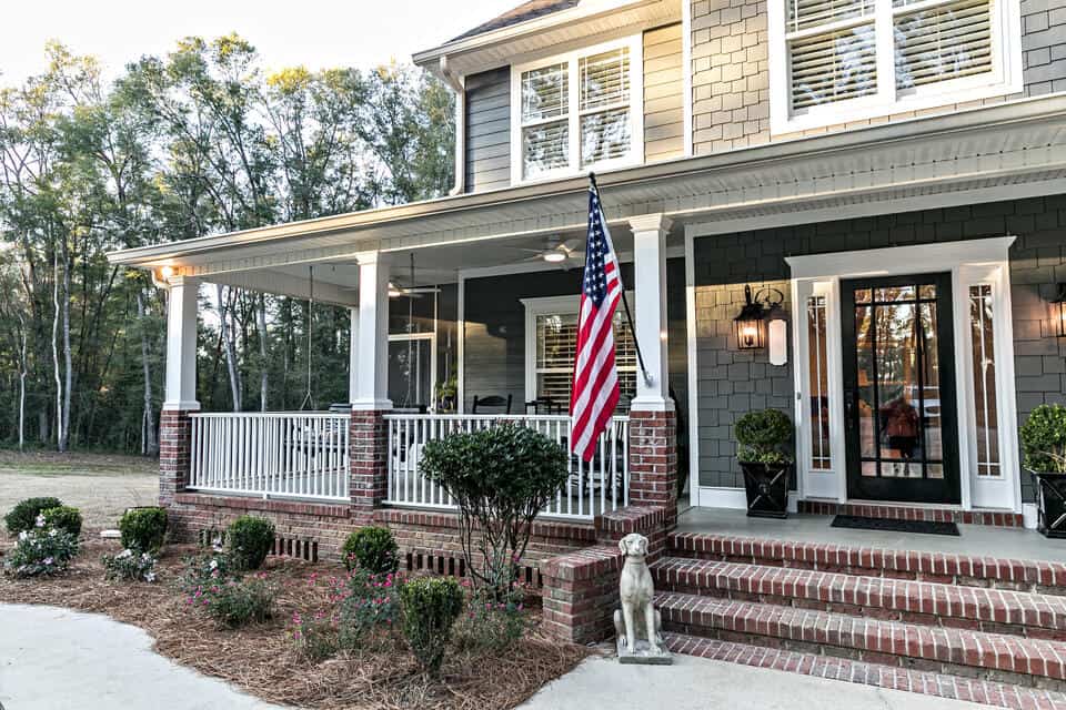 double hung window-gray sided house with brick edges on the porch and several double hung windows