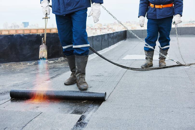 flat roof leak repair-two repair techs applying roofing materials to flat roof