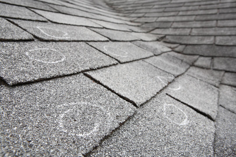 hail damage roof repair-close up image of shingled roof with marked spots of hailed damage