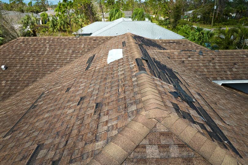 missing shingles-top view of a home's roof with sections of missing shingles