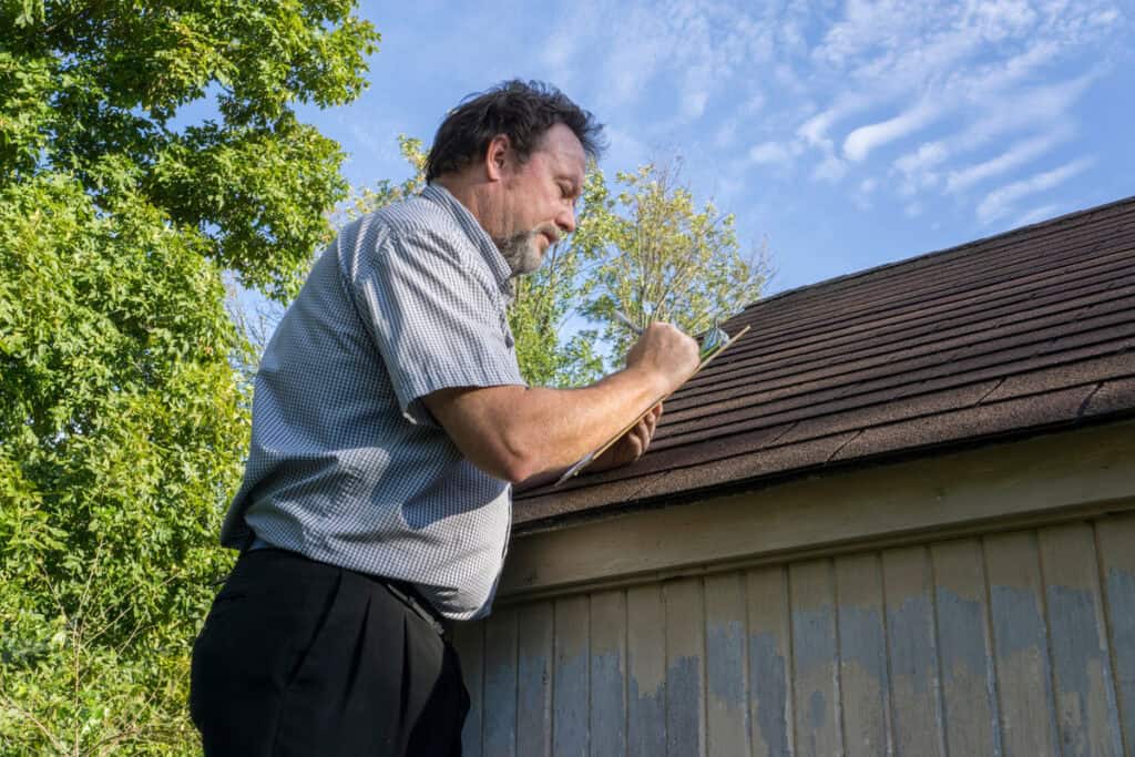 roof inspection checklist-roof inspector on a ladder against a roof with a checklist