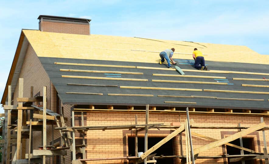 two roof techs applying roof underlayment to a roof